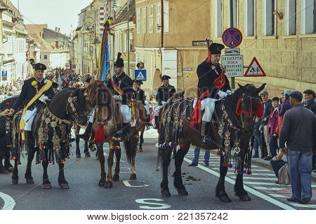 Brasov, Romania - April 27, 2014: Horsemen ride thoroughbred stallions adorned with traditional decorations during the Youths of Brasov (Junii Brasovului) Parade.