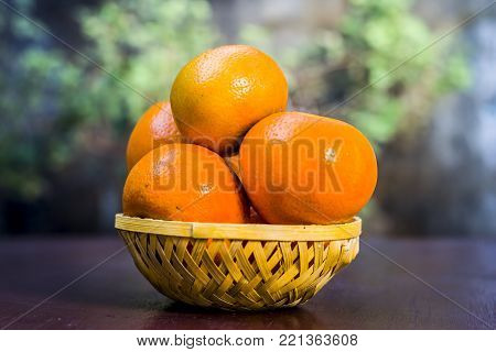 Close up of fresh ripe oranges,Citrus aurantium in a basket on wooden surface.