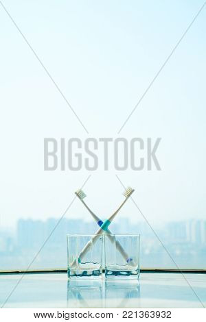 Lovers' toothbrushes in front of the window.