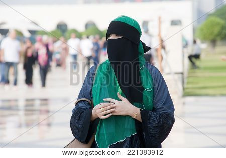 ABU DHABI, UNITED ARAB EMIRATES - DEC 28, 2017: A veiled muslima woman outside the Sheikh Zayed Mosque in Abu Dhabi.