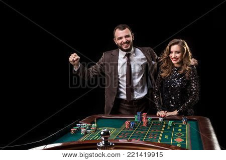 A man in a suit with a woman in a beautiful black dress playing roulette at the casino. Gambling. Casino. Roulette. Poker.