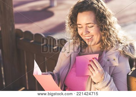 Young beautiful woman reading a love letter on Valentines / Womens Day at the park.