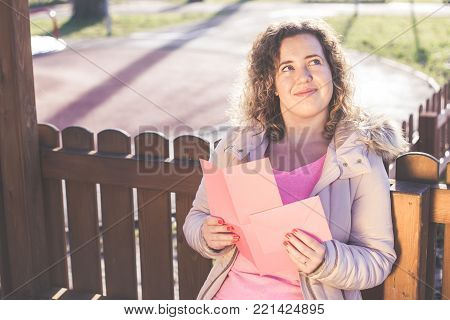 Young beautiful woman reading a love letter on Valentines / Womens Day at the park.