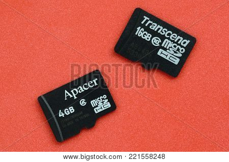 KHARKOV, UKRAINE - DECEMBER 29, 2017: Two small micro SD memory cards Apacer 4gb and Transcend 16gb lies on a red background. Illustrative editorial