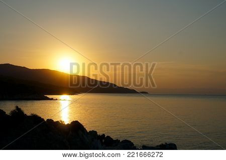 Sunset At The Sea. Sun Falling Down Behind Mountain