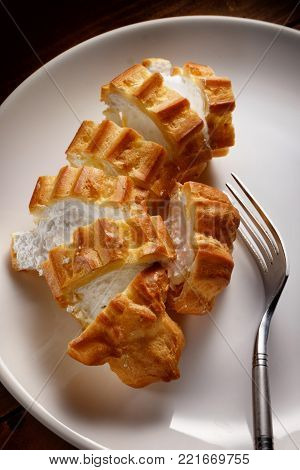 Cutted eclair on a white plate, top view