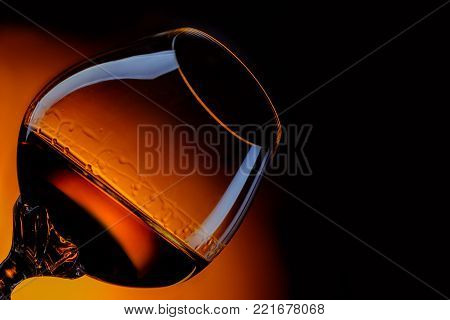 Glass of cognac close up in front of orange gradient background
