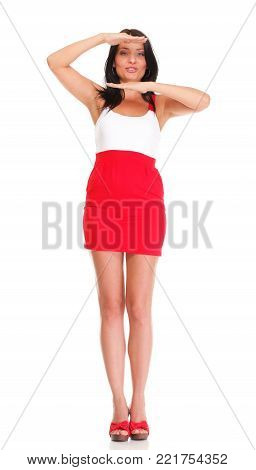 Portrait of sexy brunette in red gressi, high heels posing istudio over white isolated