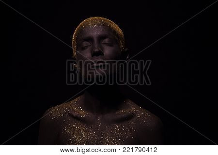 Portrait of a beautiful woman with creative body art glowing make up. Face is colored with black paint.