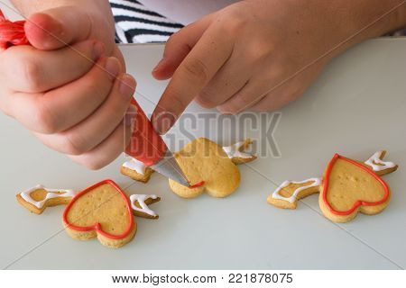 women in the kitchen prepare for the Valentine's Day. woman prepares Valentine's Day cookie. adorns heart shapes with his hands. ornamentation and shaping