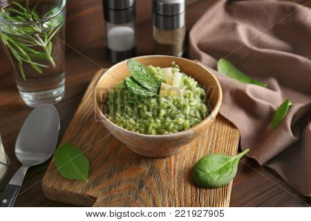 Dish with delicious spinach risotto on wooden board