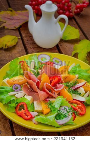 Autumn salad of jamon, lettuce, tomatoes, cheese. Wooden rustic background. Top view Selective focus