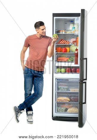 Man standing near refrigerator full of different products, on white background