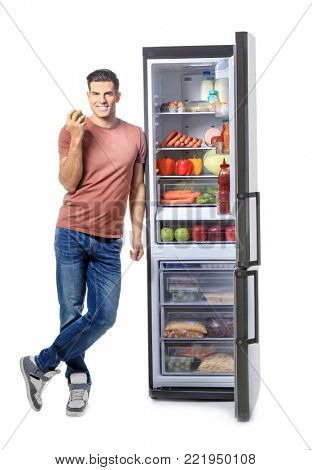 Man standing near refrigerator full of different products, on white background