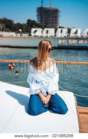 beautiful woman in a white blouse by the sea on a beach bed