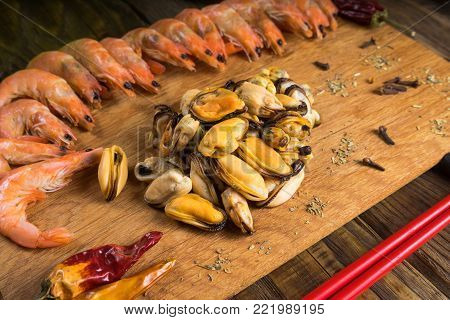 Sum tomato with shrimps and mussels on the plate on the serving Board at a beautiful stone table.