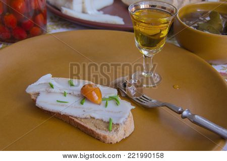 shot of alcohol a fork with a pickled mushroom and a piece of rye bread anointed with mustard and bacon on top