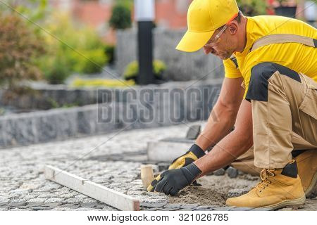 Residential Granite Brick Paving By Caucasian Construction Industry Worker.