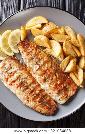 Grilled Mackerel Fillet With Potato Wedges And Lemon Close-up On A Plate. Vertical Top View