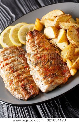 Grilled Mackerel Fillet With Potato Wedges And Lemon Close-up On A Plate. Vertical