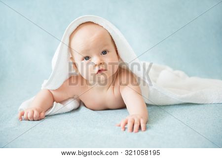 Happy Baby With A Towel After The Shower In Bed At Home