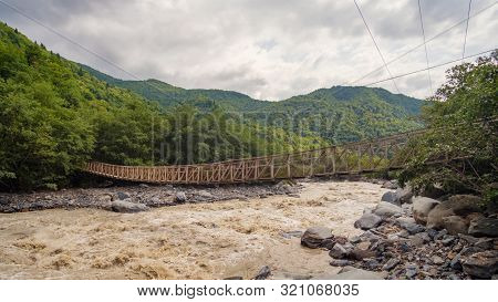 Old Hanged Rope Bridge Over The Fast Muddy River