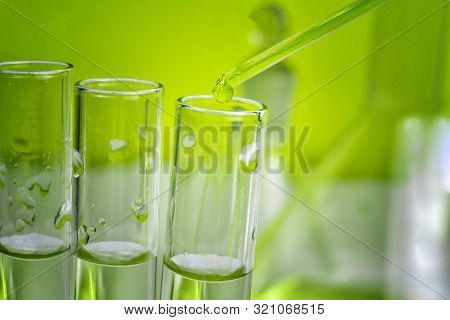 Pipette Tip With A Droplet Over A Rack Of Eppendorf Test Tubes. Close Up. Green Toning.