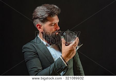 Confident Bearded Man In Black Suit With Glass Of Whisky In Loft. Confident Well-dressed Man With Gl
