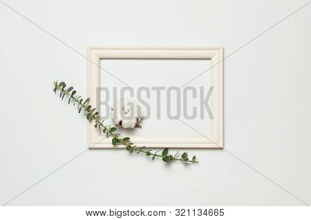 White Wooden Photo Frame And Spring Green Twigs Of Plants On Gray Background. Flat Lay Top View Copy
