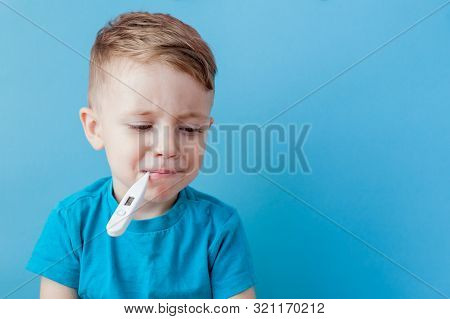 Ill Young Child With A Thermomether, Measuring The Height Of His Fever And Looking Into The Camera