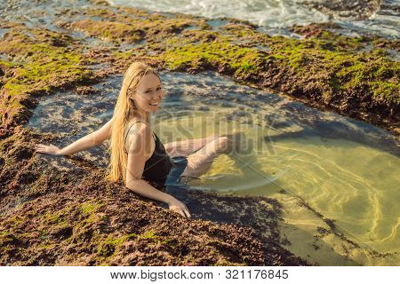 Young Woman Tourist On Pantai Tegal Wangi Beach Sitting In A Bath Of Sea Water, Bali Island, Indones