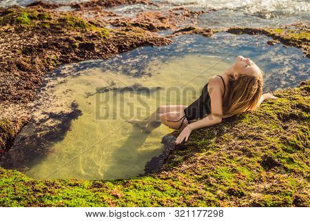 Young Woman Tourist On Pantai Tegal Wangi Beach Sitting In A Bath Of Sea Water, Bali Island, Indones
