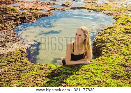 Young Woman Tourist On Pantai Tegal Wangi Beach Sitting In A Bath Of Sea Water, Bali Island, Indones