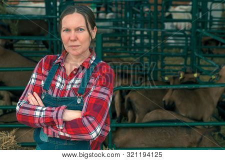 Female Farmer Posing On Goat Farm In Front Of The Goatpen