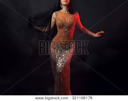 The Body Of A Beautiful Girl In A Bead Costume For Belly Dance On A Black Background Of A Stormy Sky