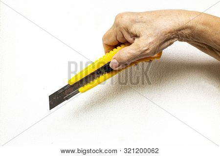 Senior Woman's Hand Holding A Cutter Knife On White Background