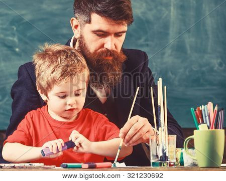 Teacher With Beard, Father And Little Son In Classroom While Drawing, Creating, Chalkboard On Backgr