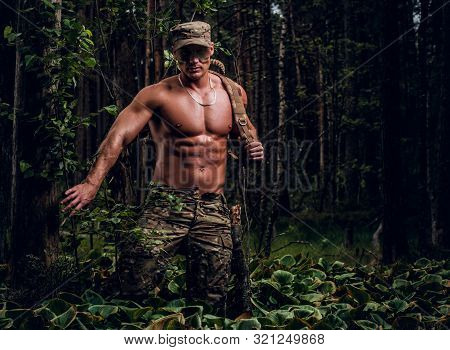 Brutal Muscular Man In Military Uniform And Naked Torso Is Posing For A Photographer In The Forest.