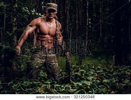 Brutal Muscular Man In Military Uniform And Naked Torso Is Posing For A Photographer In The Forest.