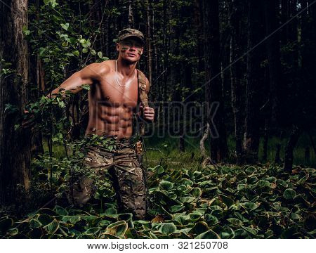 Brutal Muscular Man In Military Uniform And Naked Torso Is Posing For A Photographer In The Forest.