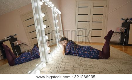The Girl Is Lying In Front Of The Mirrors And Flirting With Herself. Manufacture Of Make-up Mirrors.