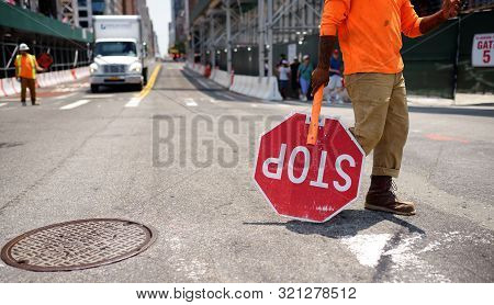 New York, Usa - July 9, 2019: Black Road Worker Carries A Stop Sign Down A New York City Street. He 