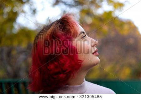 Beautiful Woman With Red Dyed Hair And Background Of Autumn Yellow Leaves.