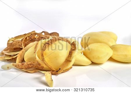 Cooking In The Kitchen. A Group Of Peeled Fresh Potatoes And Potato Skin. White Background, Close-up