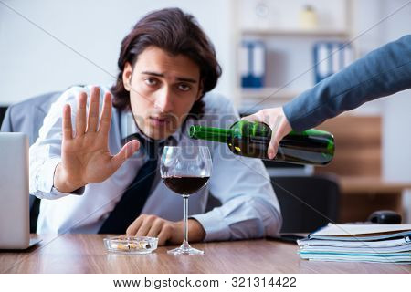 Male employee drinking alcohol and smoking cigarettes at workpla