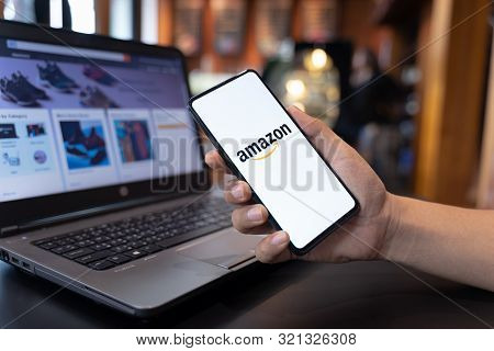 Chiang Mai, Thailand - May.01,2019: Man Hands Holding Xiaomi Mi Mix 3 With Amazon Apps And Laptop At