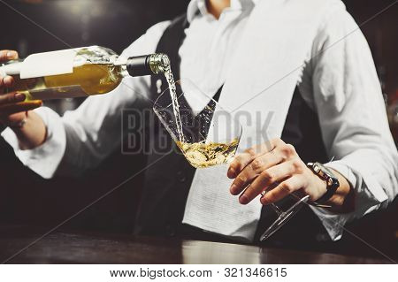 Sommelier Pours White Wine From A Bottle Into Glass At The Bar, Close-up.