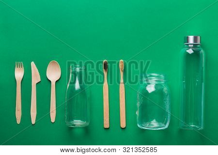 Bamboo Toothbrushes Wooden Cutlery Glass Bottle Jar On Green Background. Zero Waste Plastic Free Eco