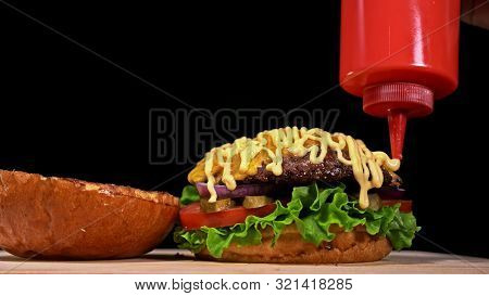 Craft Burger Is Cooking On Black Background. Consist: Sauce, Lettuce, Tomato, Red Onion, Pickle, Che
