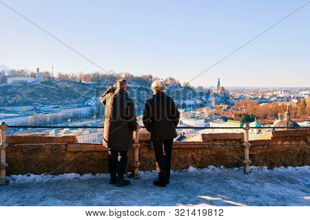 Senior Couple Looking At Panorama Of Salzburg With Snow